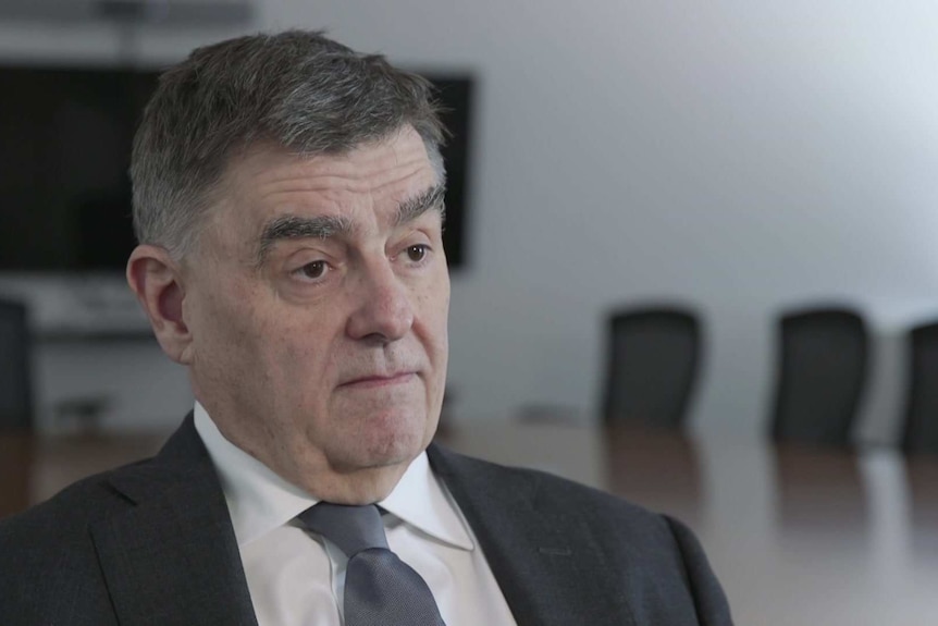 Chief Medical Officer Brendan Murphy sitting in a chair with a boardroom table behind him