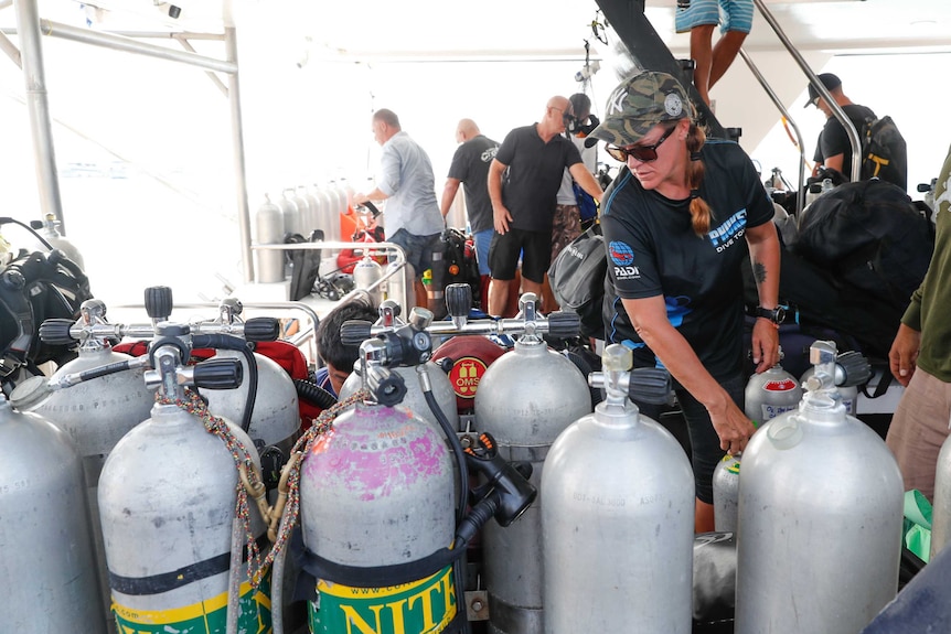 Divers check oxygen tanks on a boat as they prepare to recover bodies of passengers of a capsized tourist boat in Phuket.