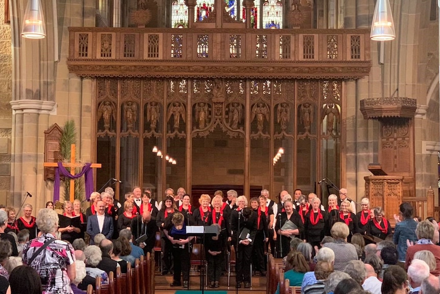 A choir stands in front of an audience in a cathedral 