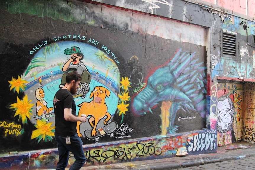A man walks past a mural in Hosier Lane.