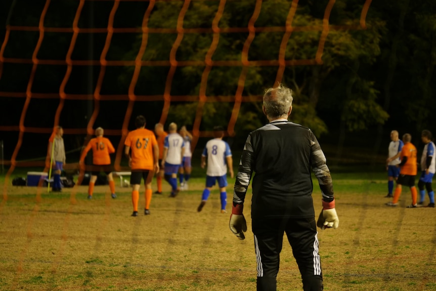 A goalkeeper watches his team play on a football field