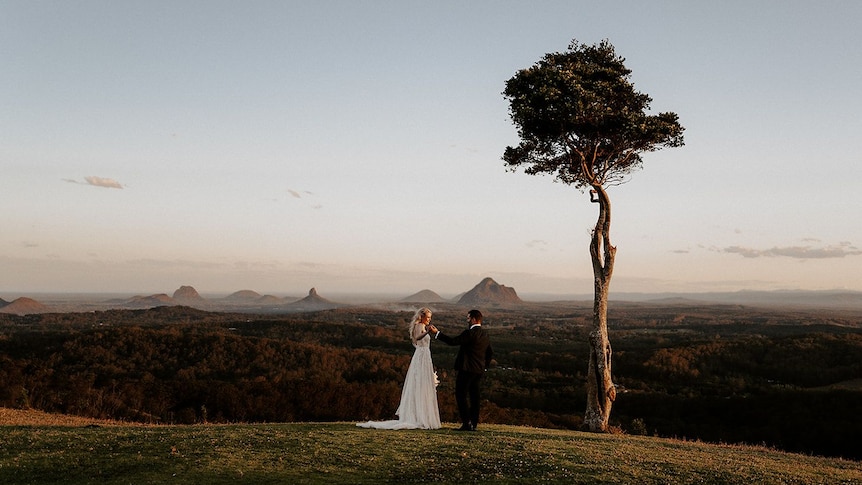 A couple photographed in a wedding dress and suit at One Tree Hill on the Sunshine Coast