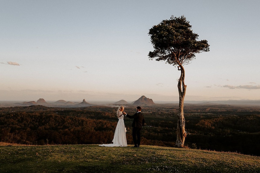 A couple photographed in a wedding dress and suit at One Tree Hill on the Sunshine Coast