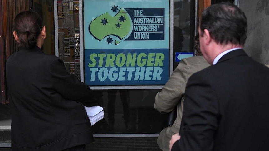 AFP officers face a sign at AWU office that says "The Australian Workers' Union Stronger Together"