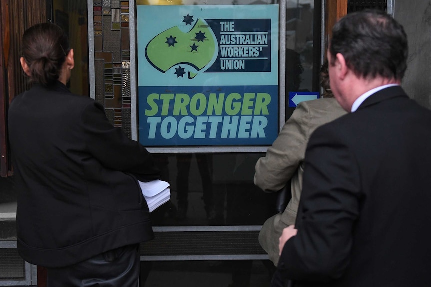 AFP officers face a sign at AWU office that says "The Australian Workers' Union Stronger Together"