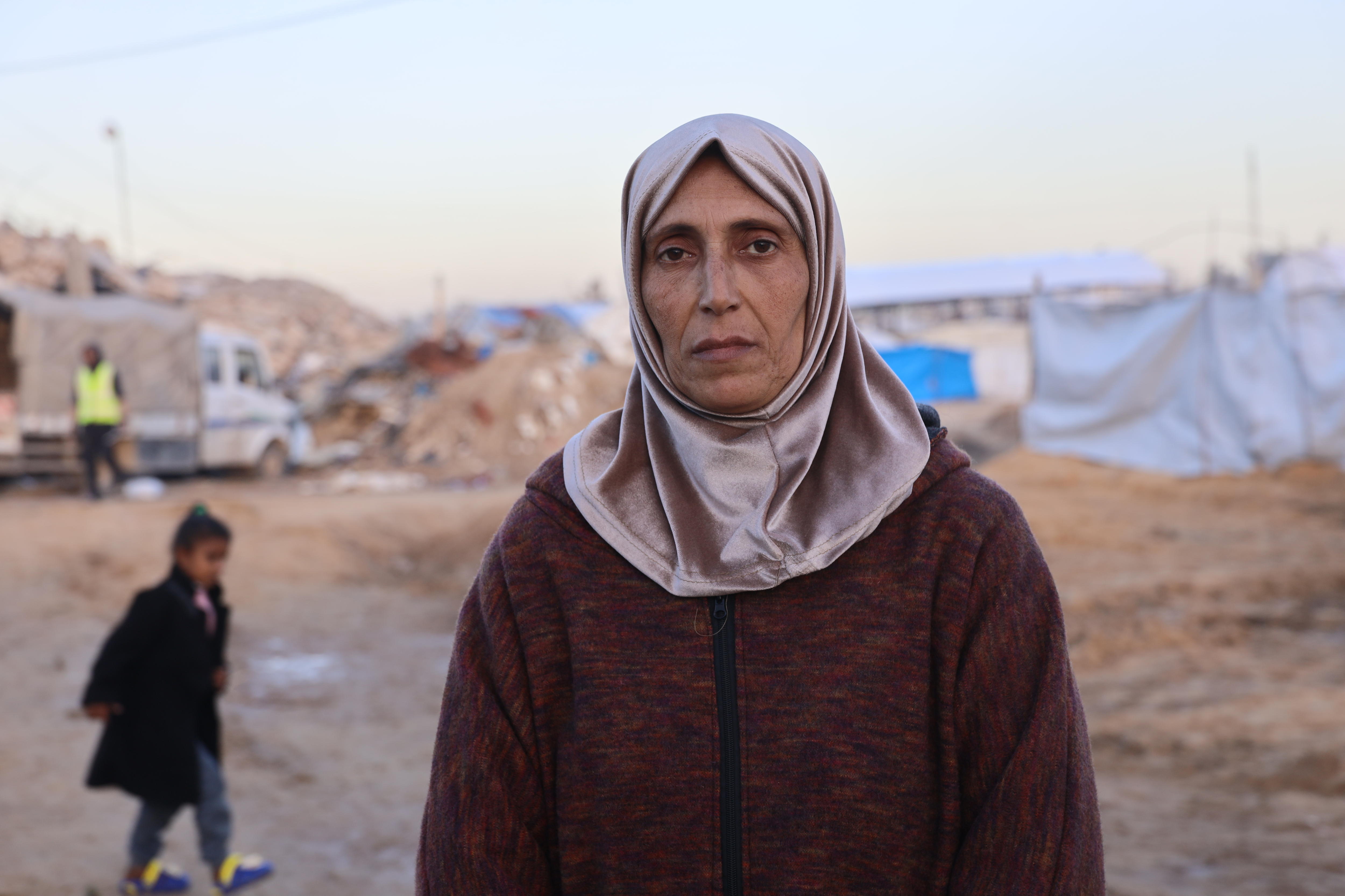 Uma mulher olha de forma neutra para a câmera contra um fundo empoeirado