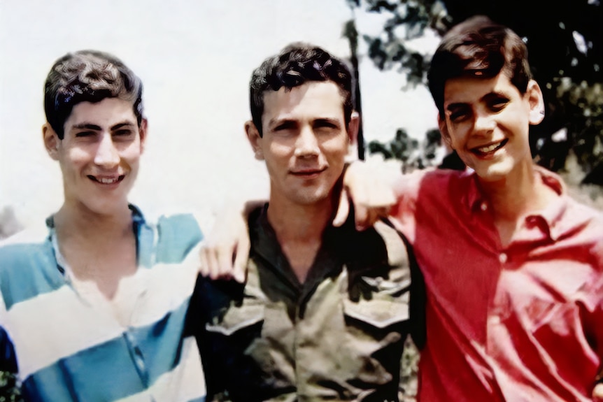 An old photo of three young men with their arms around each other, smiling.