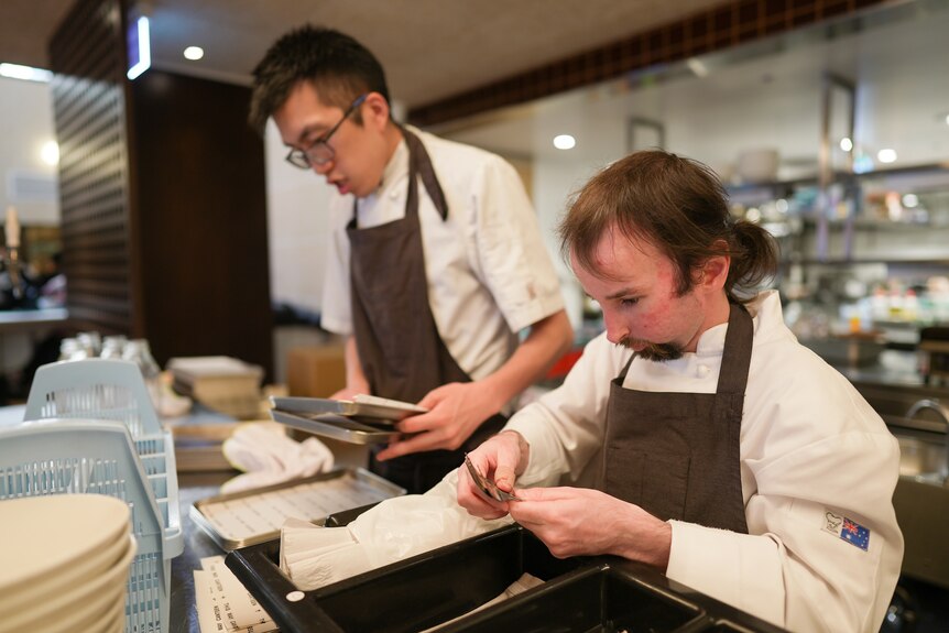 Darren and Robbie are focussing on polishing cutlery and organising dishes in the restaurant's back of house area.