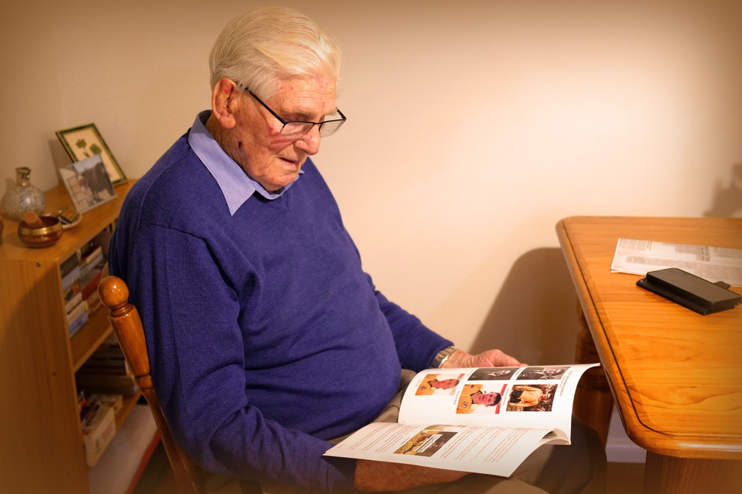 A man sitting on a chair looking at a photo album