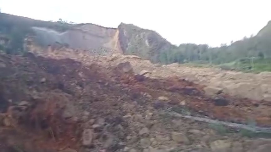 A blurry image of a landslide below a cliff.