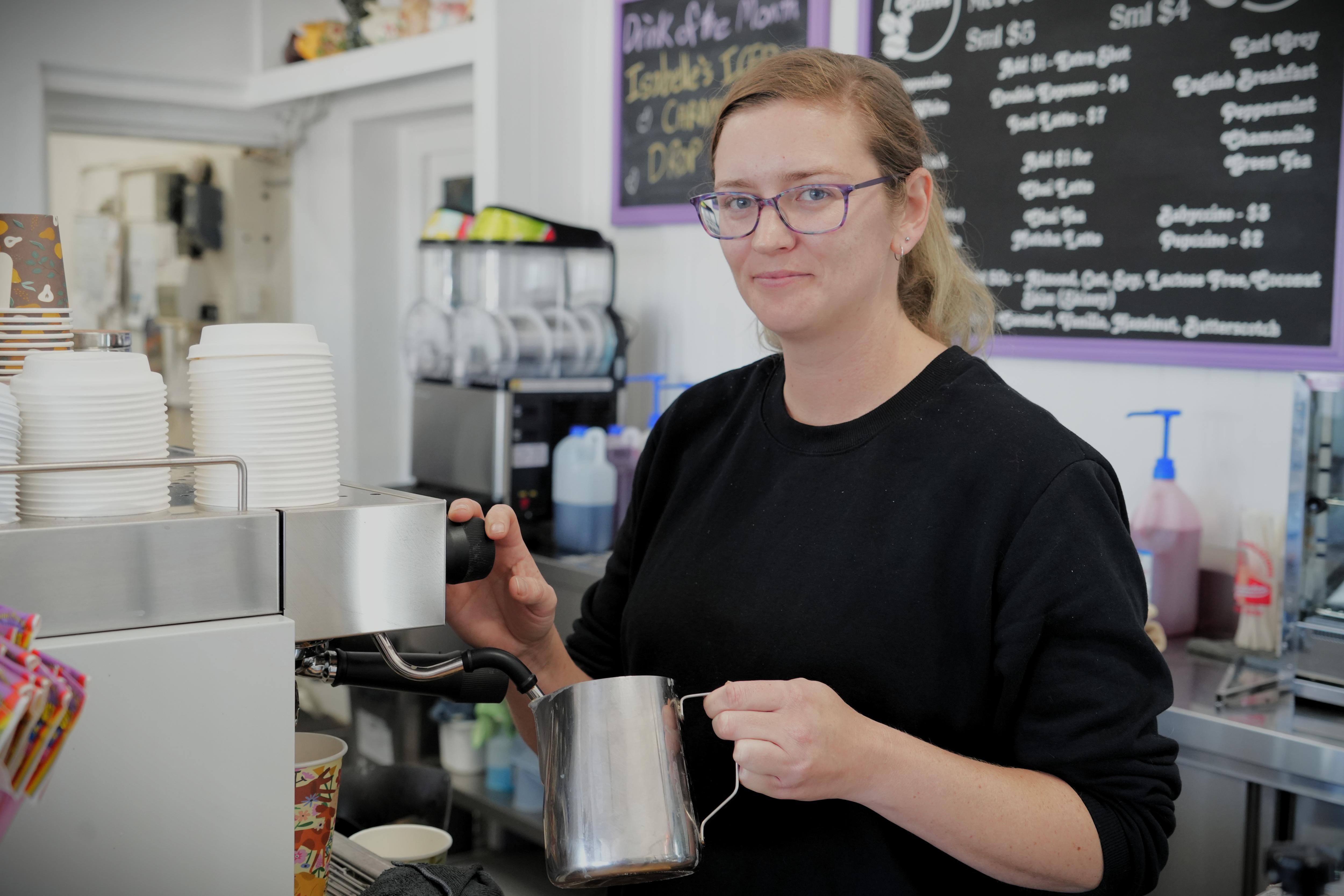 A lady makes a coffee at a machine 