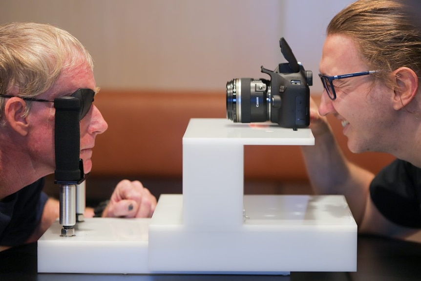 An expert photographs Craig Faull's eye while the patient is positioned in a chin rest