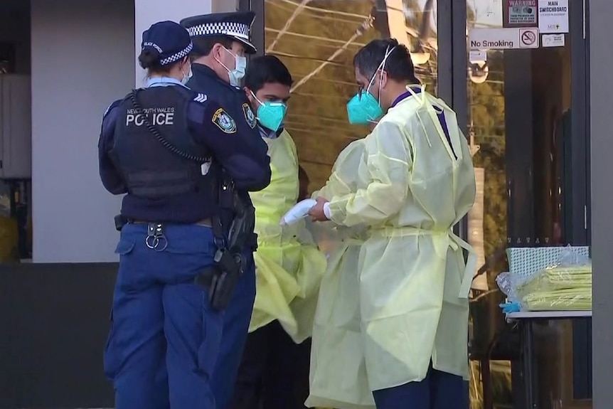 Two police and two health workers outside an apartment