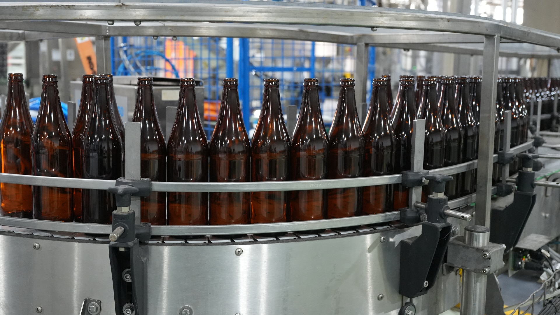Large brown glass bottles on a factory conveyer belt.