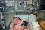 Lachlan Miles and his seizure dog Sharni lay asleep in an emergency bed.