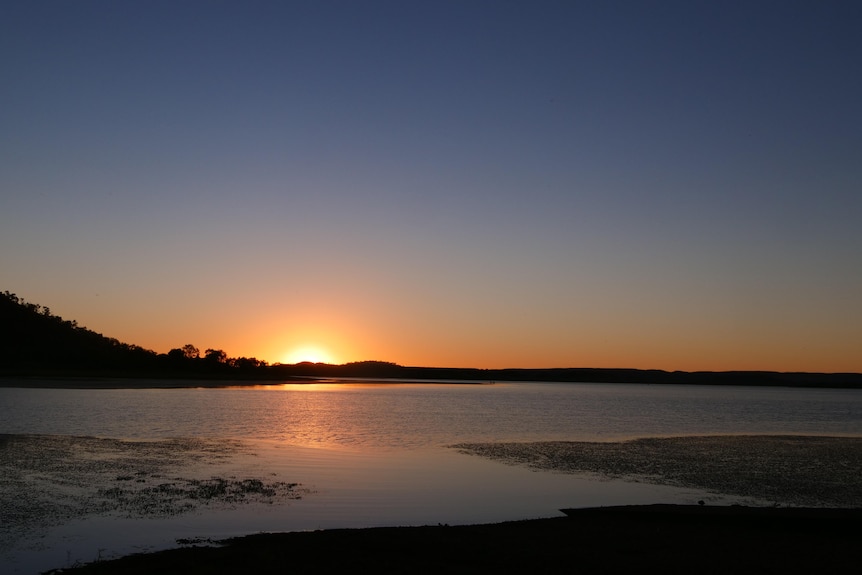 a sun sets over a lake