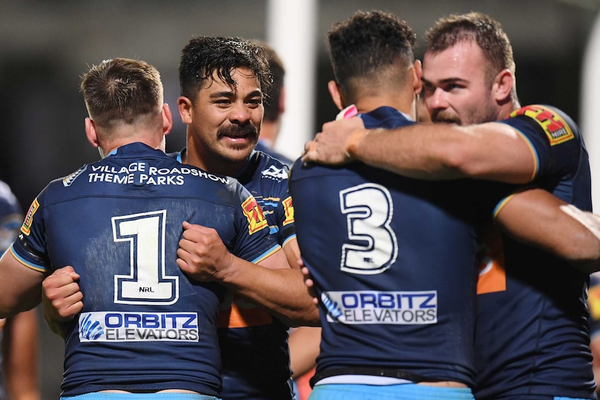 Four Gold Coast Titans NRL players embrace each other after they beat St George Illawarra Dragons.