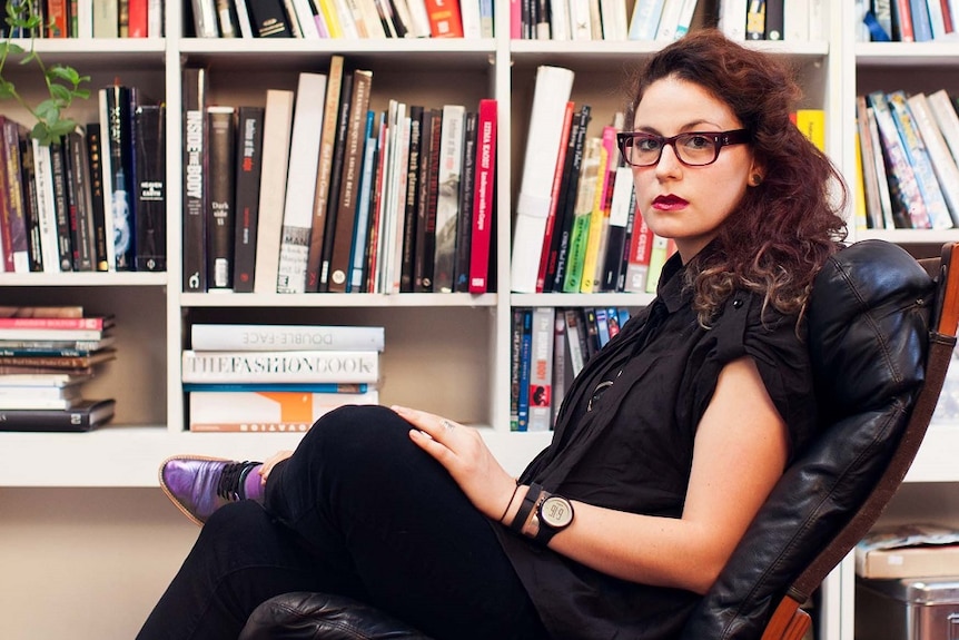 Pia Interlandi sits in front of a book case to depict theories about denim, such as buying jeans too tight.