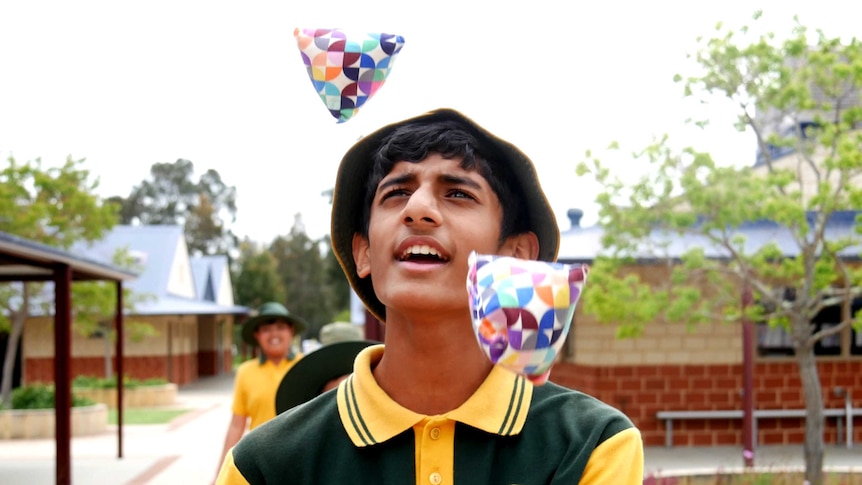 A young student practises juggling in a school courtyard.