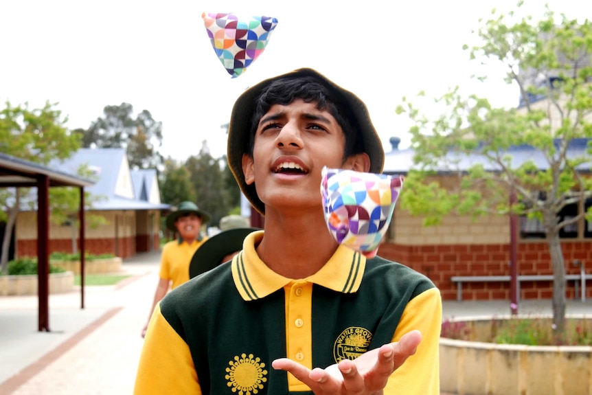 A young student practises juggling in a school courtyard.