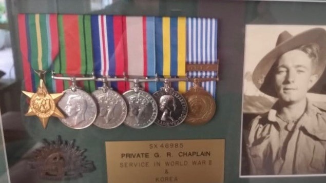 A plaque with a historical photo and replicas of army medals 