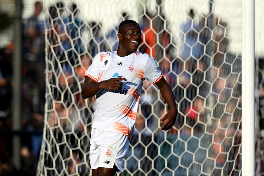 Cyrus Dehmie looks back over his shoulder smiling with a net in the background