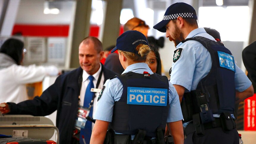Two officers in caps talk to passengers