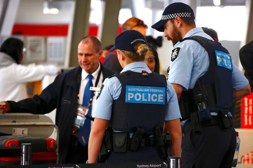 Two officers in caps talk to passengers