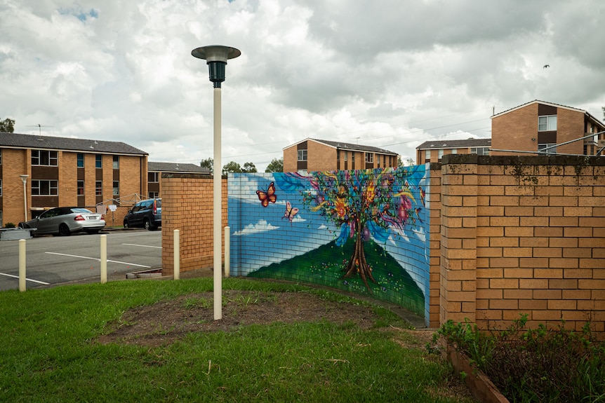a drawing on a brick wall of a colourful tree surrounded by butterflies