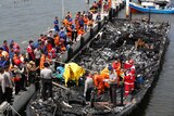 Indonesian police and rescue workers inspect a burnt-out boat at Muara Angke port.
