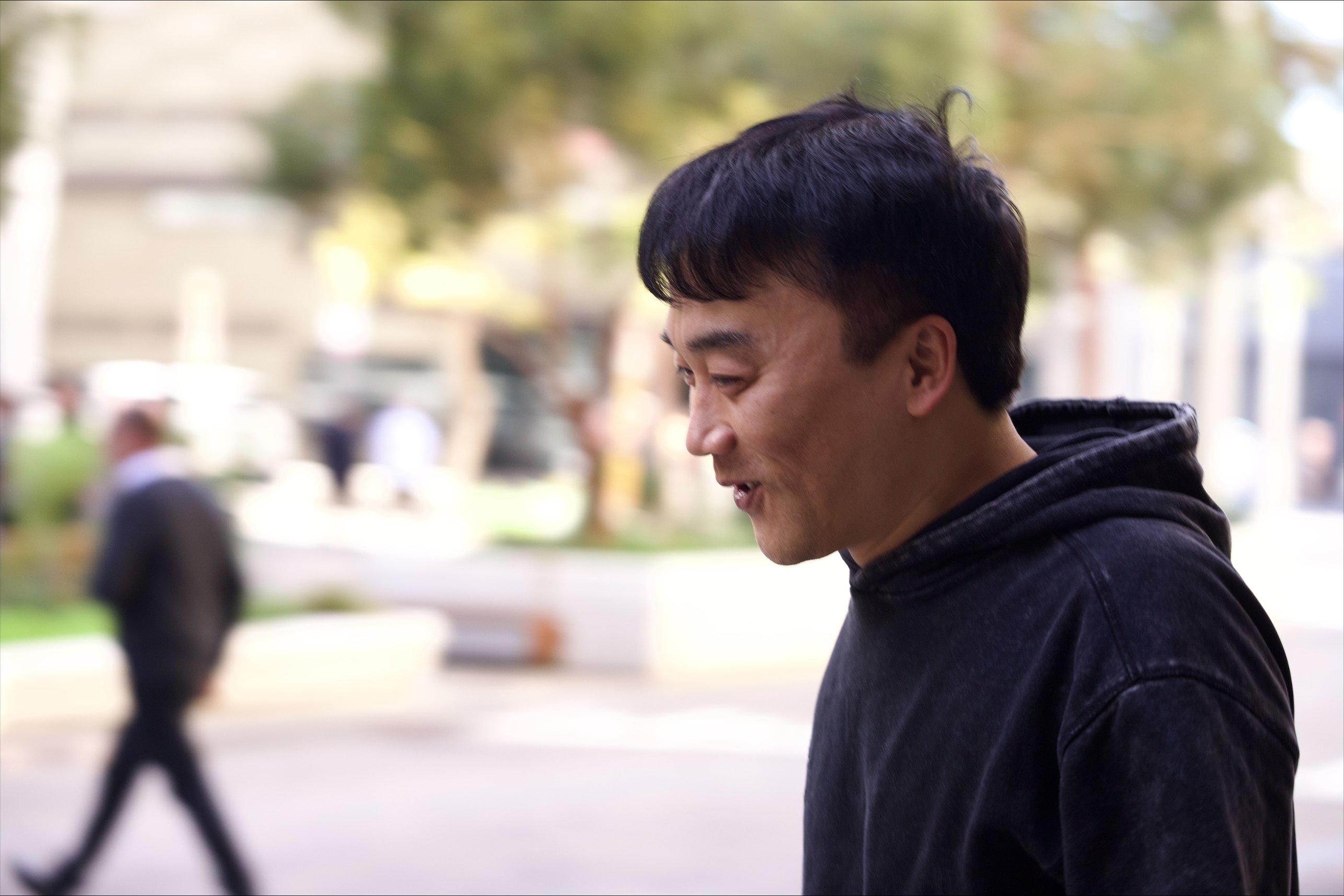 The side profile of a man wearing a black hooded jumper