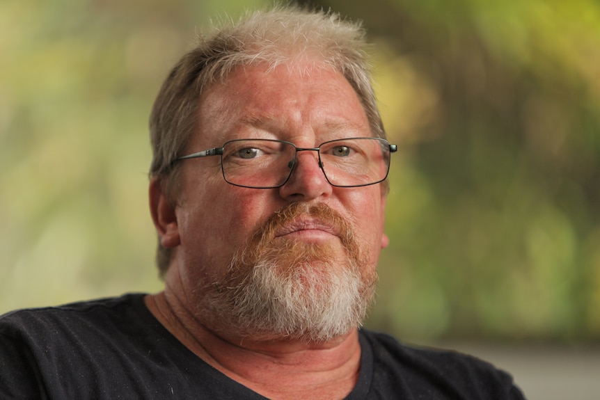 Man wearing a black shirt and glasses with a beard. 