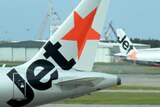 Two Jetstar planes taxi past each other at Brisbane Airport.