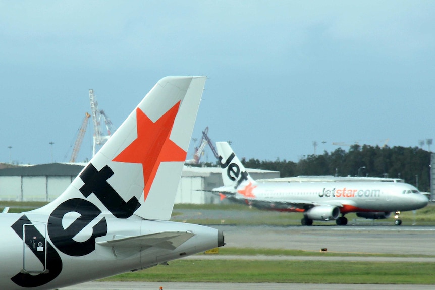 Two Jetstar planes taxi at Brisbane Airport.