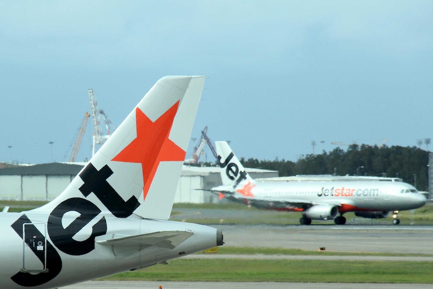 Two Jetstar planes taxi past each other at Brisbane Airport.