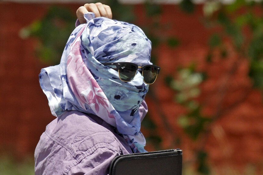 Woman covers face from sun during heatwave in India