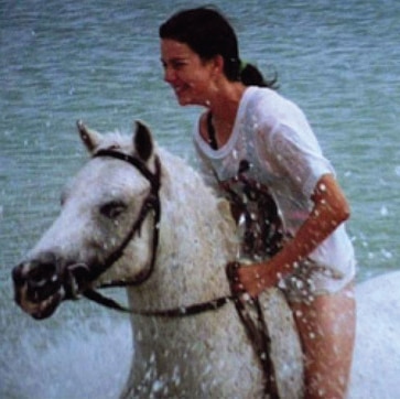 Amanda rides a horse through the ocean.