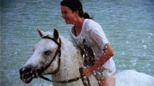 Amanda rides a horse through the ocean.