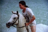 Amanda rides a horse through the ocean.