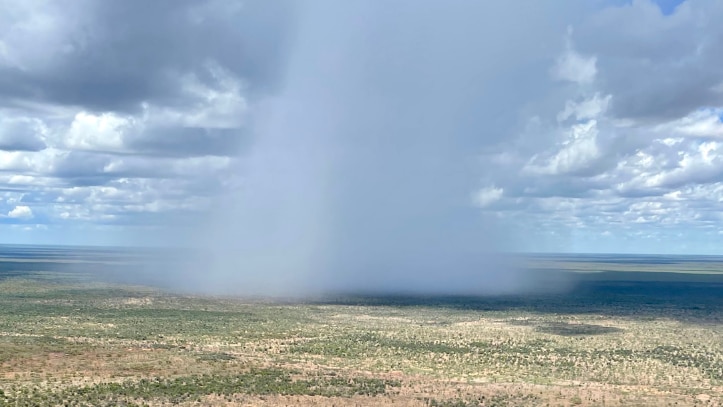 an aerial photo of an isolated storm falling on a cattle station.