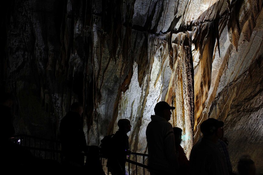 People standing on a path in the cave watching the performance.