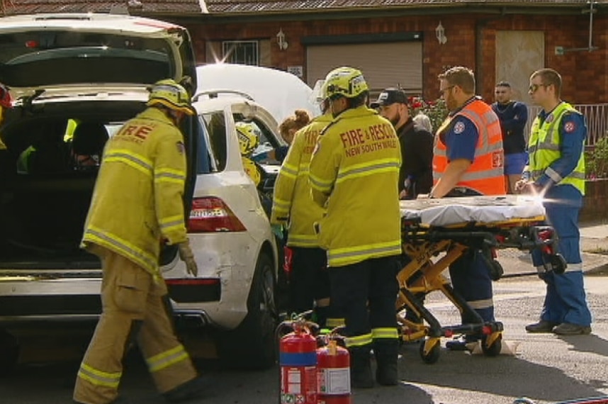 Several people stand around a car.