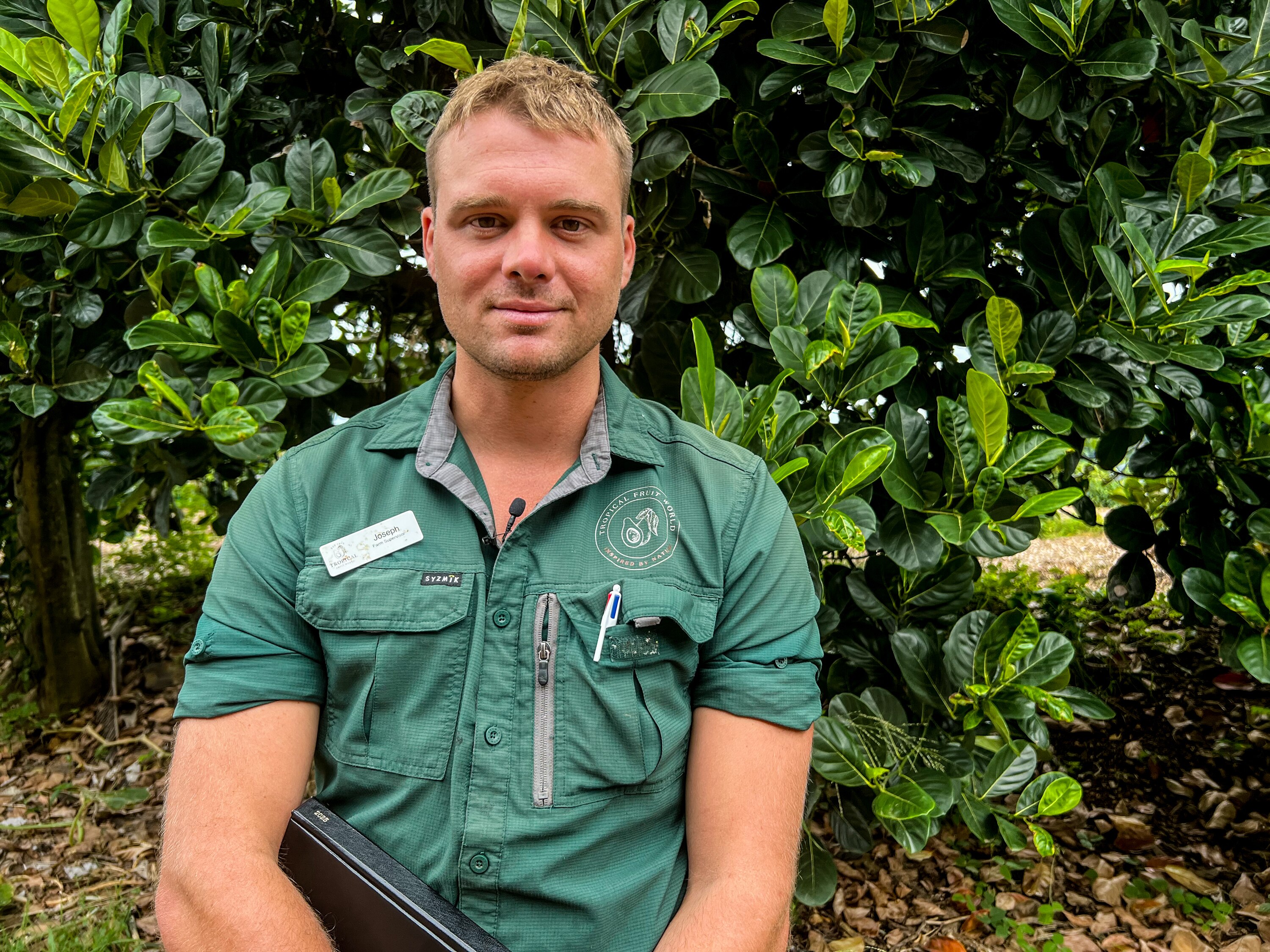 A man wearing a green shirt smiles at the camera.