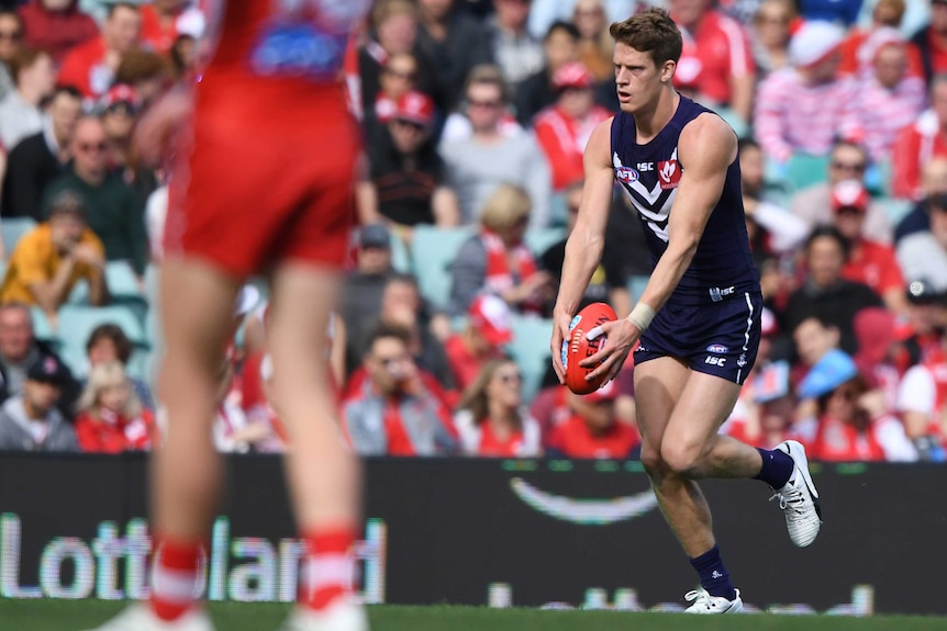Fremantle Dockers forward Matt Taberner kicks for goal in an AFL match with a Sydney Swans player in the foreground back turned.