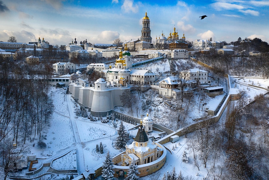A beautiful complex of old buildings and gold-domed churches covered in snow