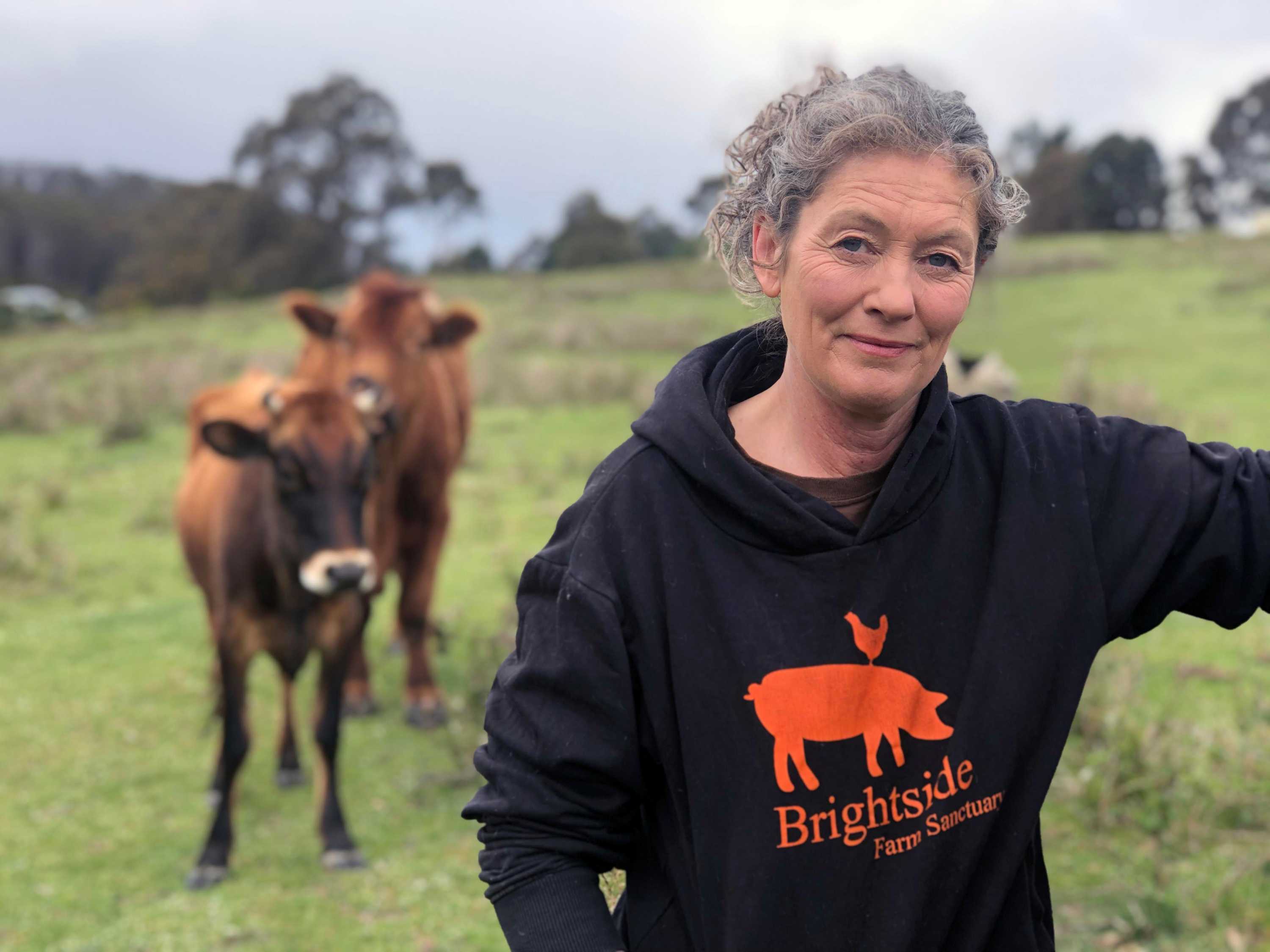 Emma Haswell stands next to cattle at Brightside Farm Sanctuary