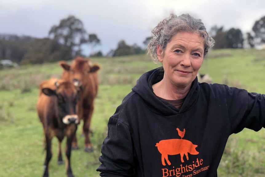 Emma Haswell stands next to cattle at Brightside Farm Sanctuary