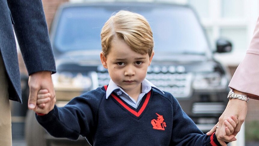 Prince George holds his parents hands and looks coy on his first day of school.