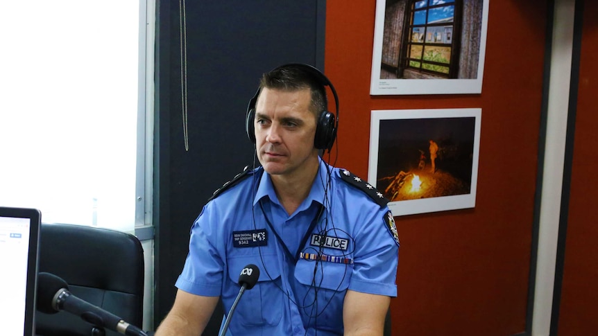 Senior Sergeant Dean Snashall sits in an ABC studio with headphones on in his police uniform