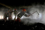 Firefighters uses axes to clear debris through a dark, smoky building